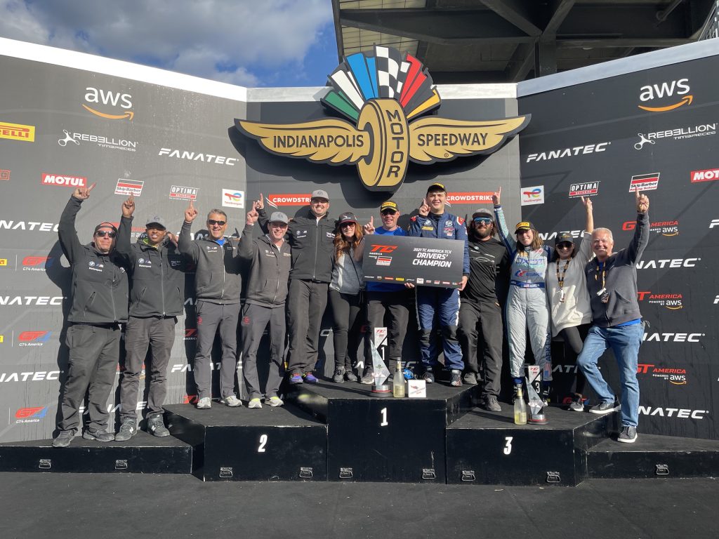 Fast Track Racing crew celebrating a championship on the Indianapolis Motor Speedway podium