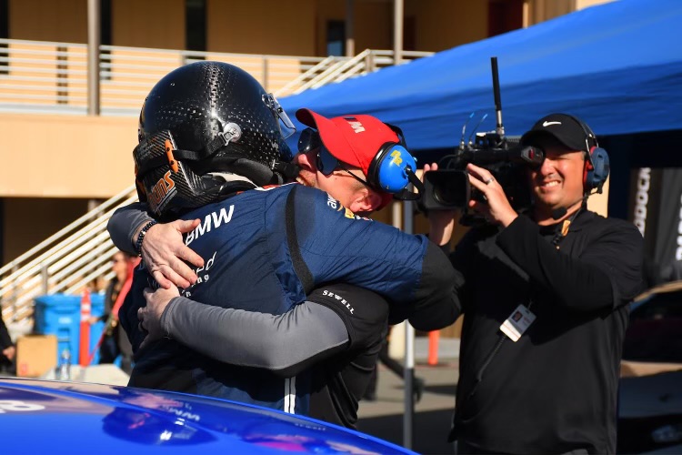 Nick celebrating with a driver trackside as TV cameras roll